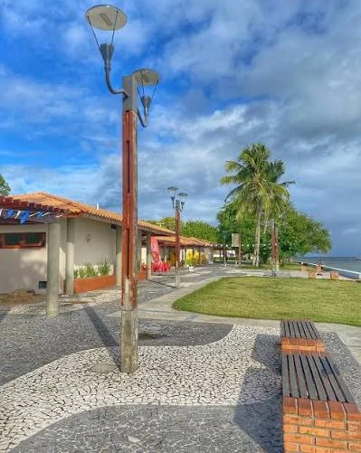 Praça e orla de Cacha-Pregos, com bancos, coqueiros e calçamento