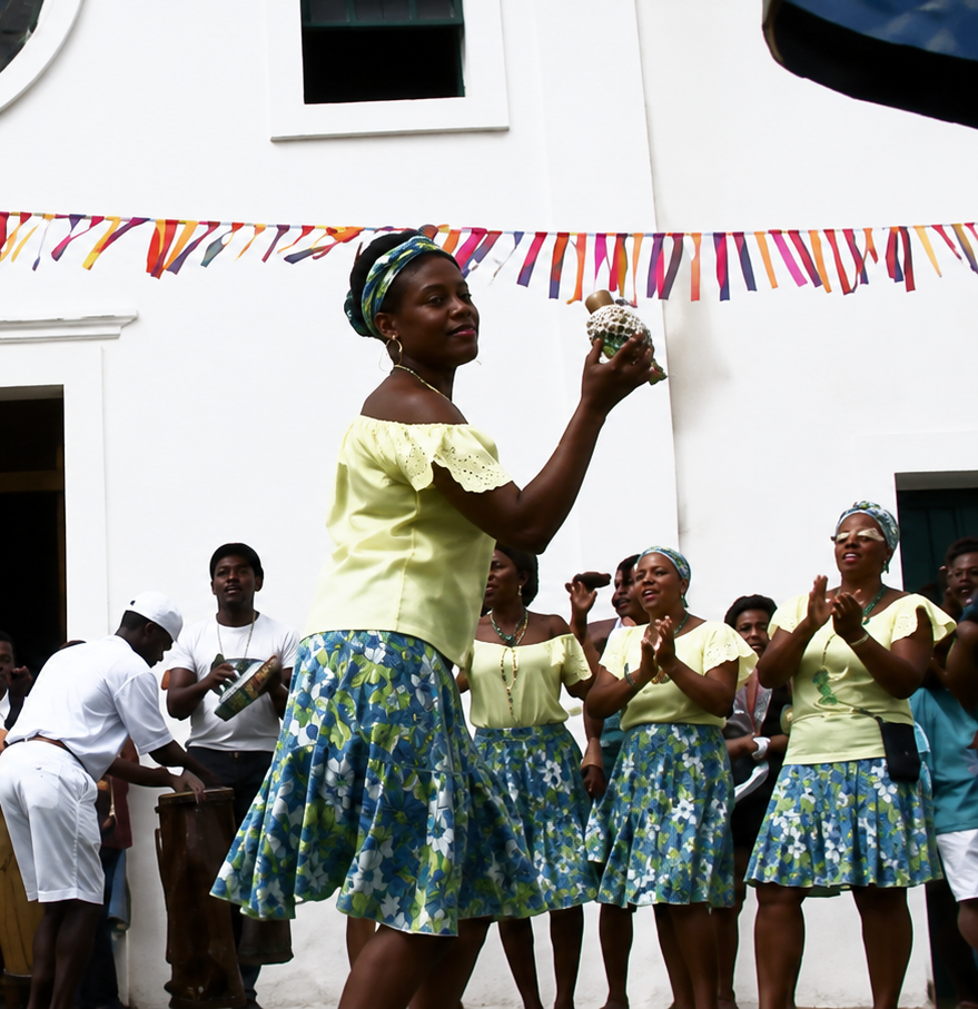 Mulheres dançando samba de roda diante de uma igreja