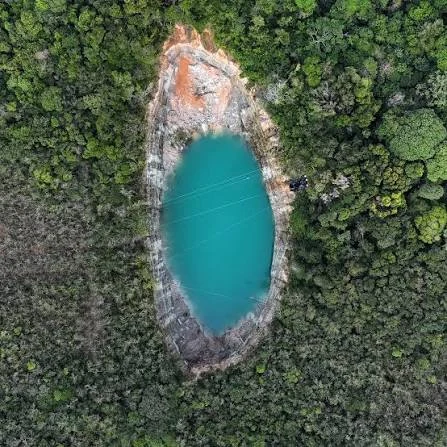 Cavidade de formato oval preenchida por água e cercada por vegetação
