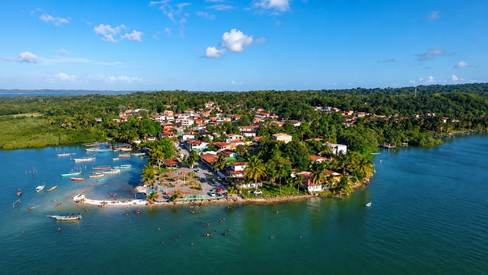 Vista aérea da Vila de Matarandiba, cercada por águas, vegetação, casas e pequenas embarcações