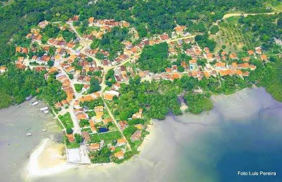 Vista aérea de Matarandiba com casas, vegetação, faixa de areia e águas rasas