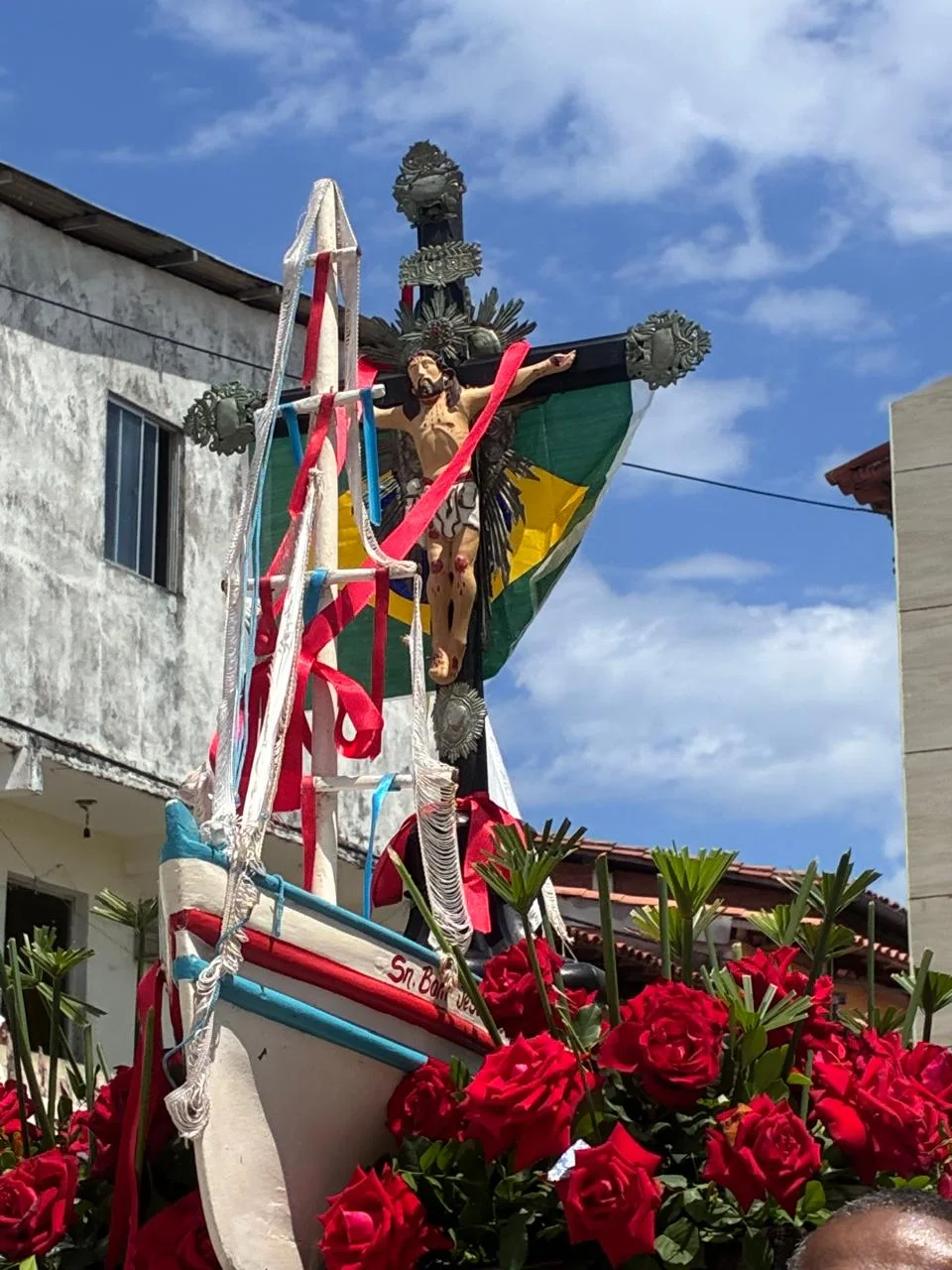Imagem religiosa conduzida em embarcação decorada com flores durante celebração comunitária