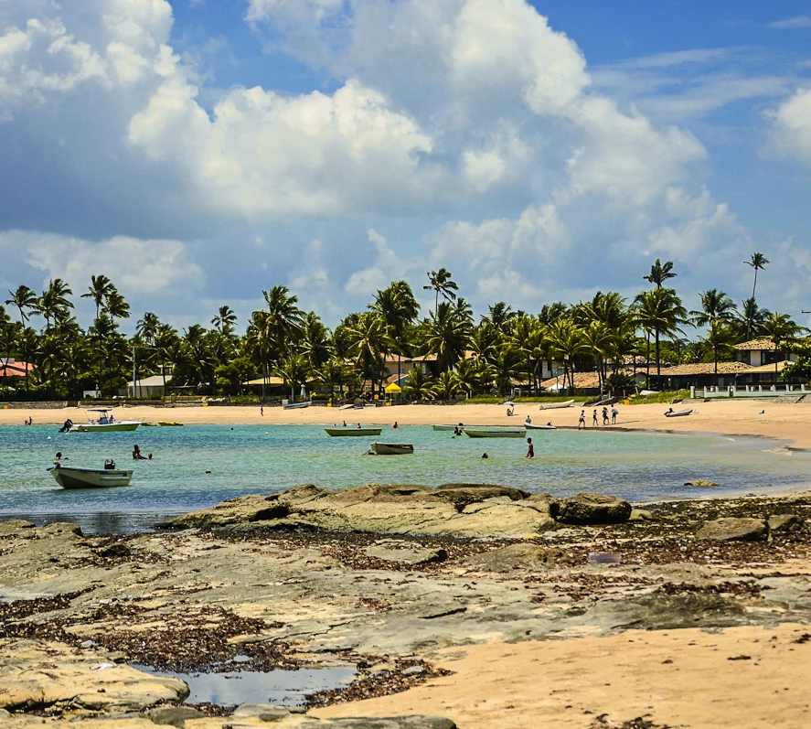 Praia da Penha com barcos, coqueiros e recifes expostos
